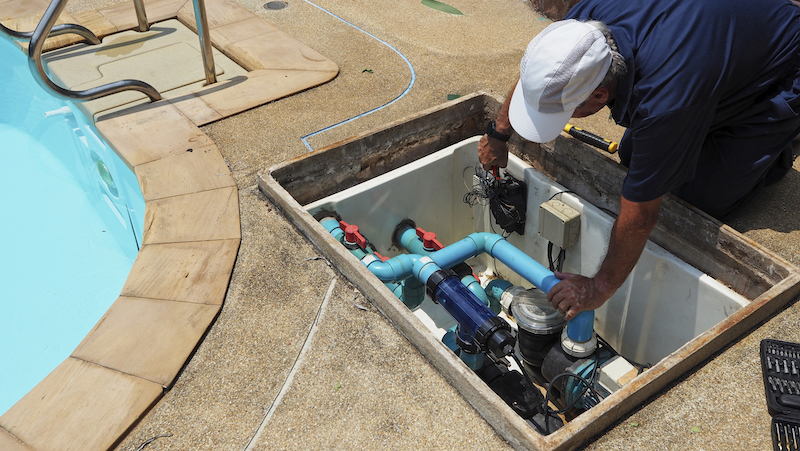 Technician fixing swimming pool water heater pump. Service and maintenance for swimming pool.