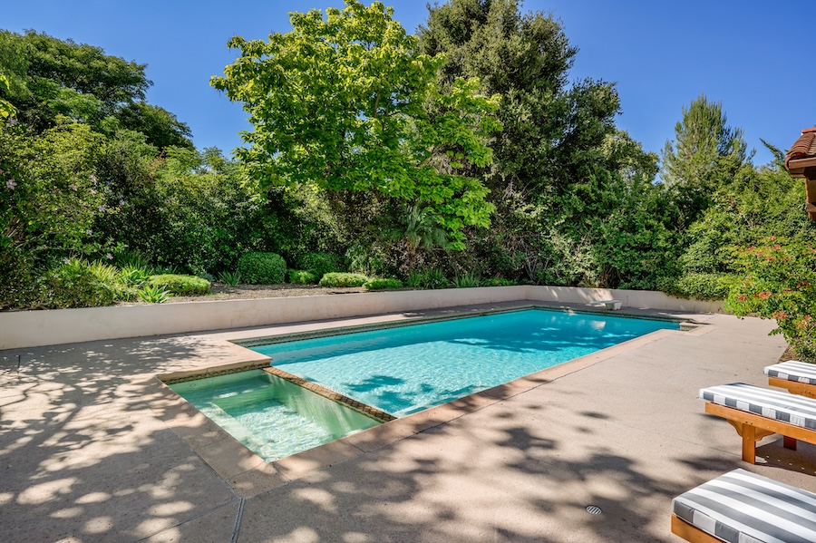 Outdoor pool with two lounge chairs and a surrounding fence