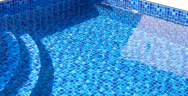 Vinyl lined pool. Outdoor photo of a mosaic-patterned residential swimming pool. Swimming pool with internal steps. Feeling of moving water.