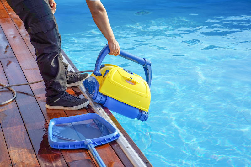 Pool cleaner during his work. Caucasian hotel staff worker cleaning the pool