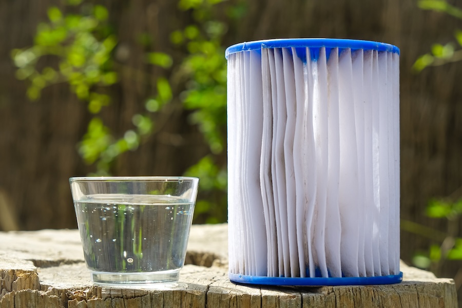 A clean pool filter next to a clear glass of water