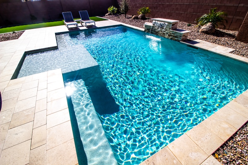 Back Yard With Two Lounge Recliner Chairs And Swimming Pool With Waterfall