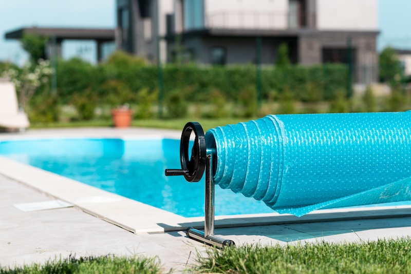 Roll up safety cover for the pool. Home pool protection concept. Relax in the backyard of a country house