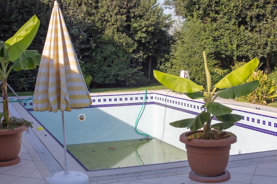 Swimming pool that is almost empty with dirty water
