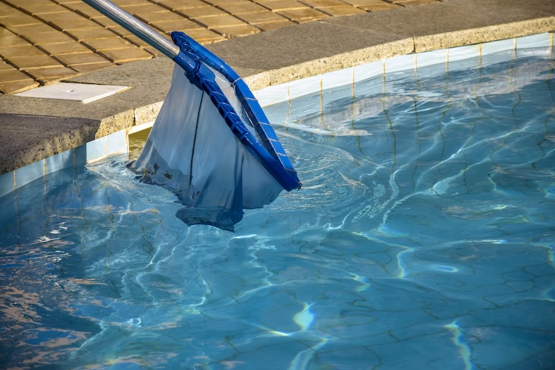 Cleaning pool from garbage with special net. Clear water with blue tint. Concept of hygiene and healthy lifestyle. Horizontal photo. Copy space. Close-up. Selective focus.