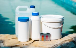 Close up photo of equipment for testing the quality of pool water and chemical cleaning products at the edge of swimming pool.