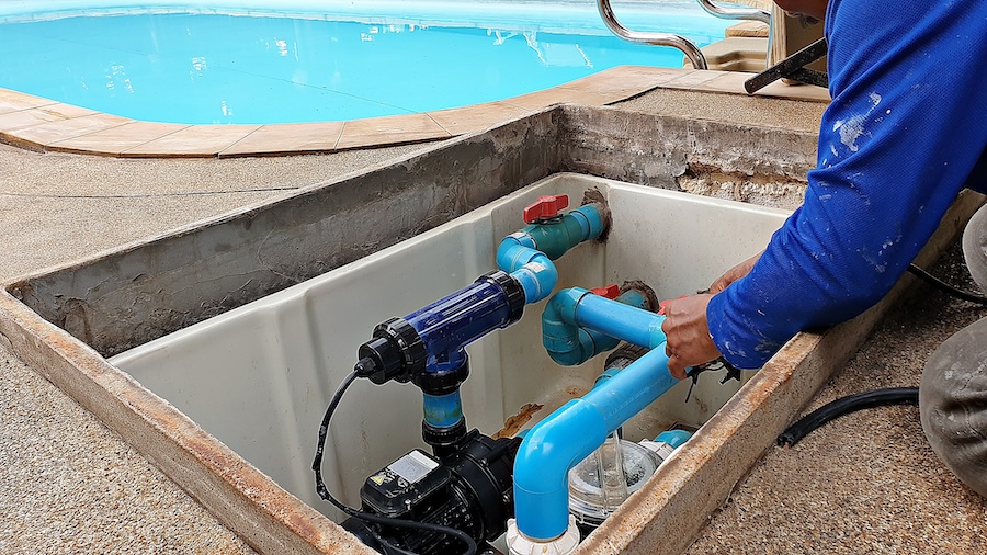 Technician fixing swimming pool water pump. Service and maintenance for swimming pool.