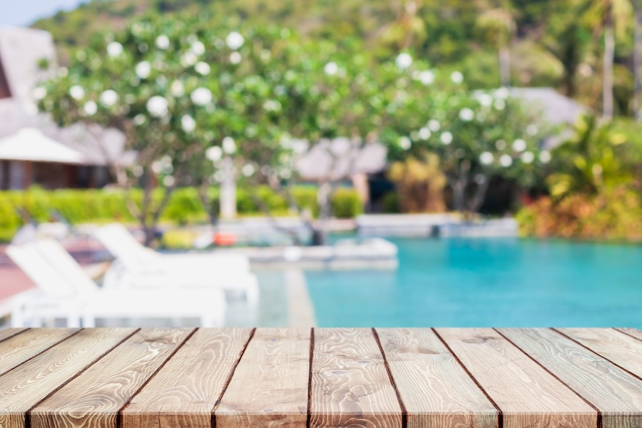 Empty wood table top and blurred swimming pool