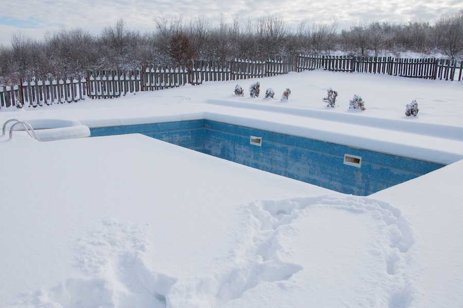 Empty icy swimming pool in the winter with snow