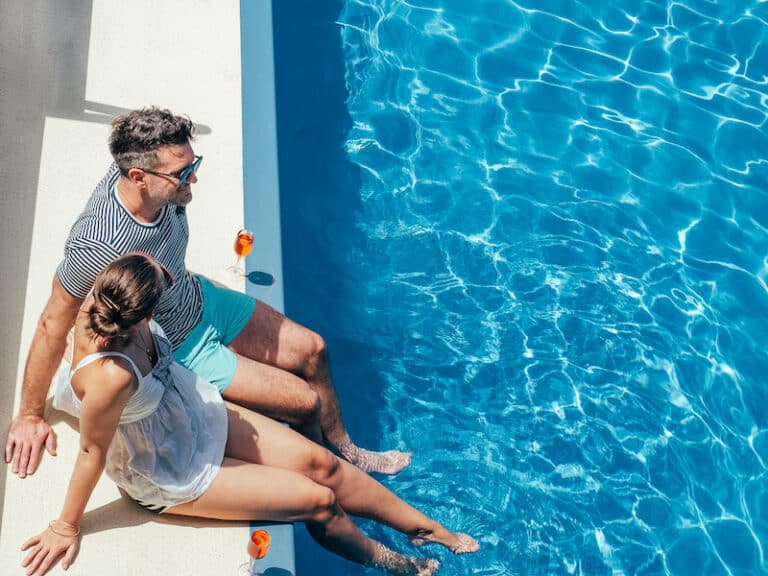 Young couple in love sitting by the pool on the empty deck of a cruise liner. Closeup, outdoor, view from above. Vacation and travel concept