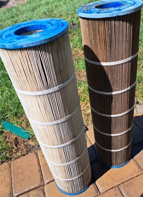 Pool filters standing up outside of pool on the ground.