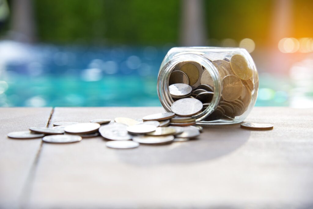 Overturned jar of coins in front of a pool. Economic concept