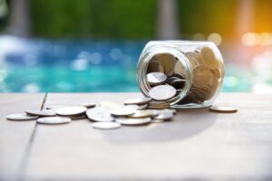 Overturned jar of coins in front of a pool. Economic concept