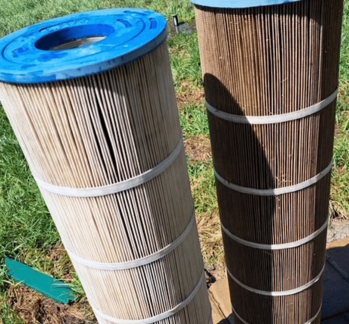 Pool filters standing up outside of pool on the ground.