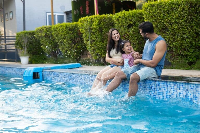 Young family enjoys swimming pool in summer