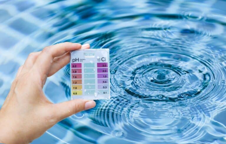 Pool tester test kit in hand over water background
