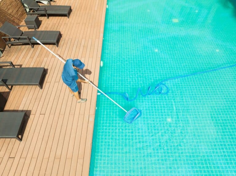 Pool maintenance technician cleaning pool with scoop net.