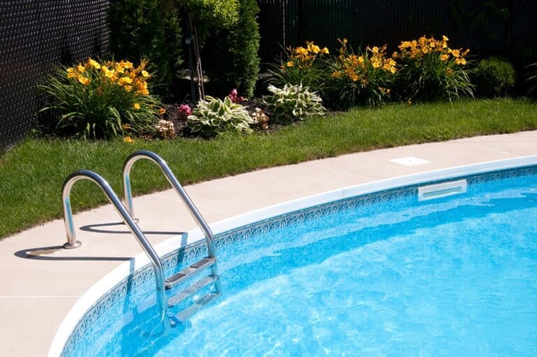 Curve side of a pool with stairs and flowers in the background