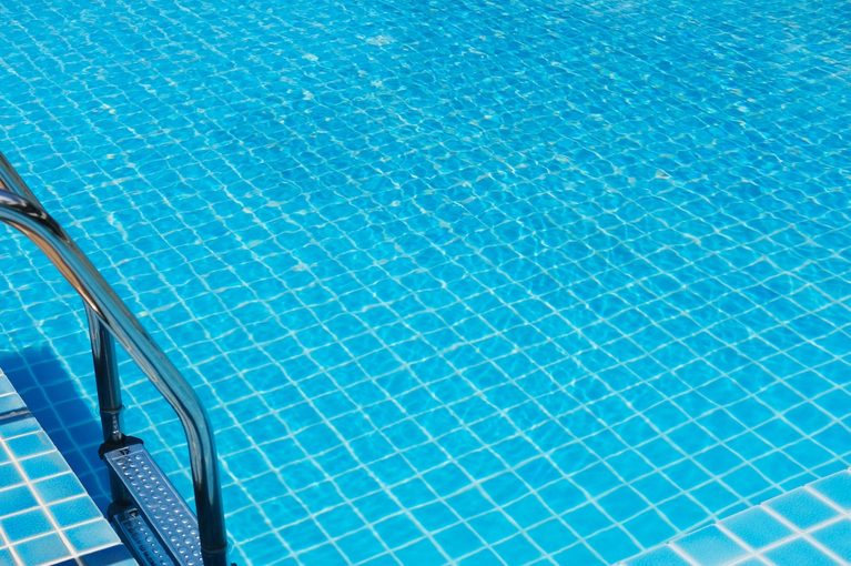Clear blue water fills a swimming pool with a tiled surface